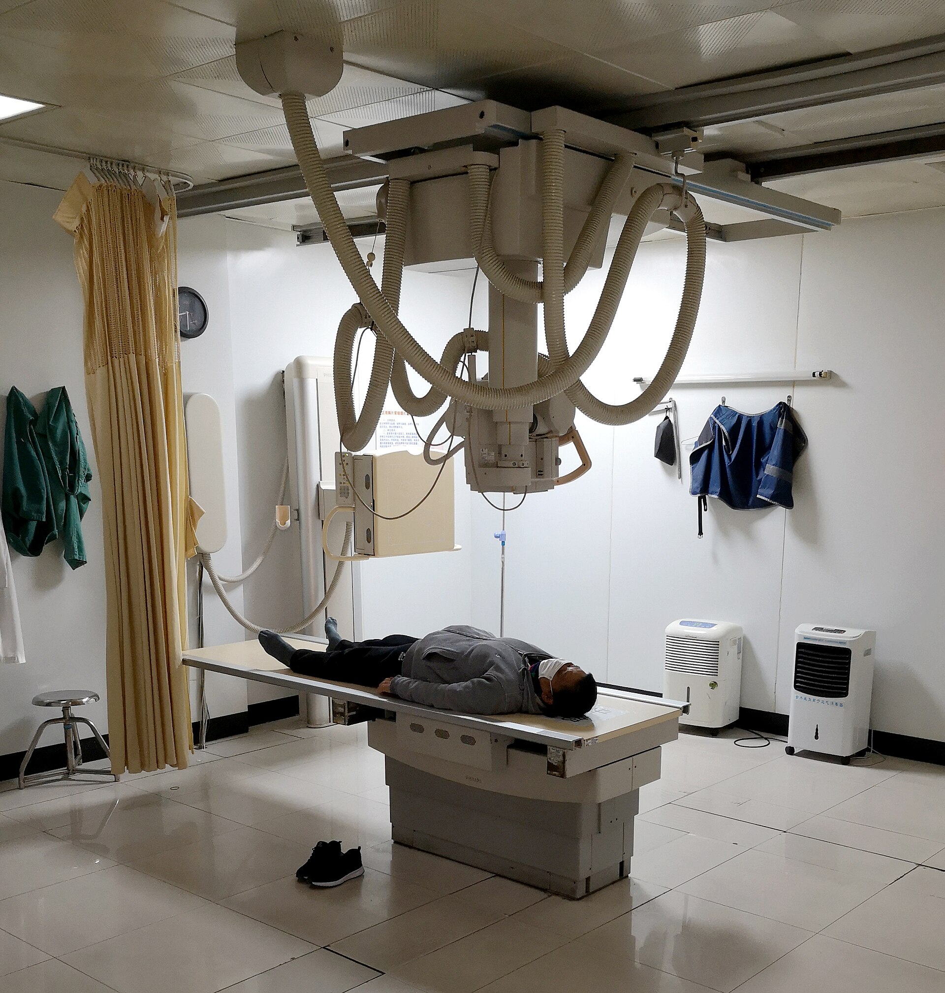 A real diagnostic X-ray room with ceiling-mounted tube, table, and wall bucky